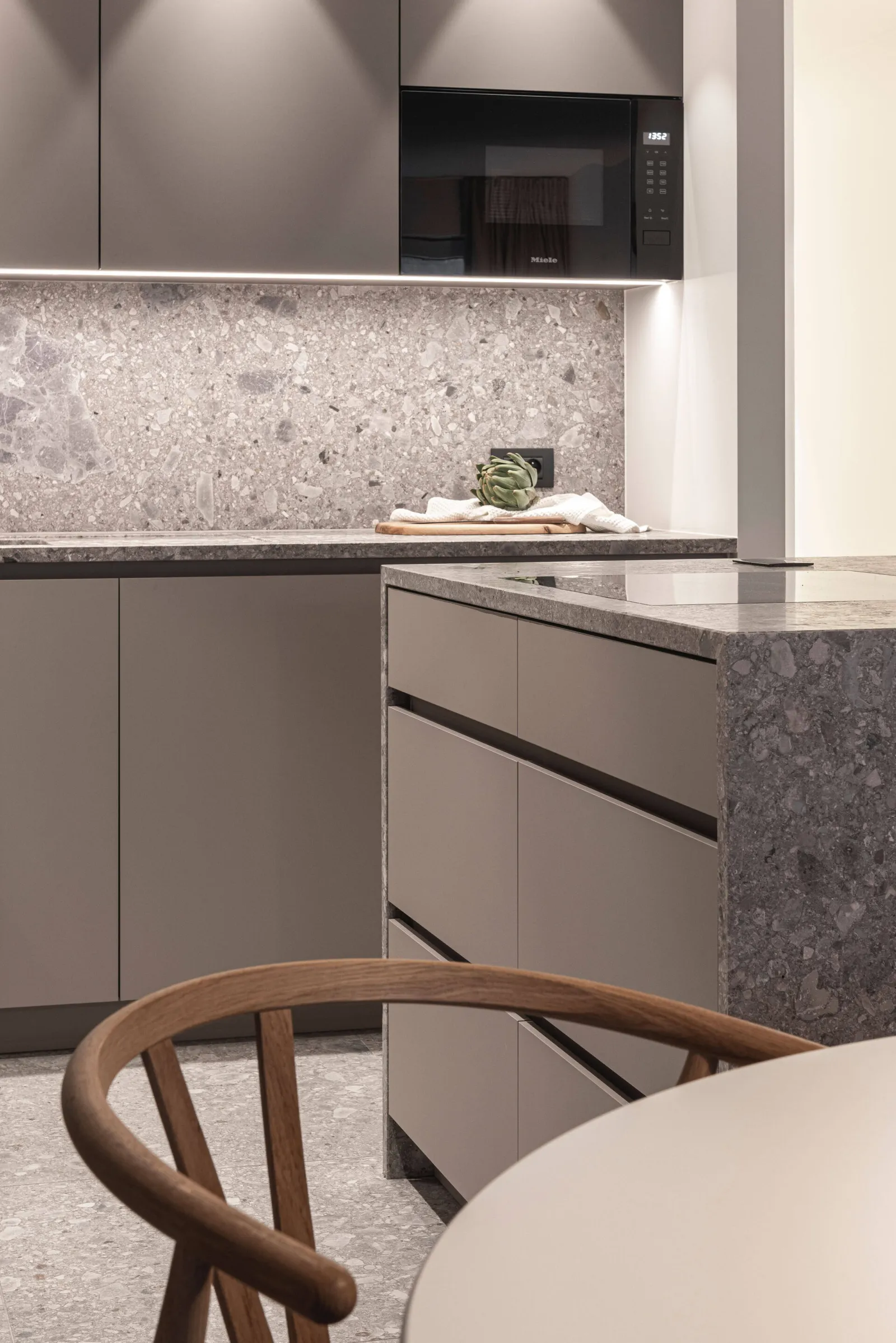 Keuken in taupe met terrazzo werkblad en houten stoel